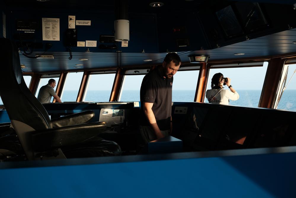 An MSF crew member watches and scans the horizon through his binoculars looking for boats in distress. (Geo Barents, February 2022, @Kenny Karpov)