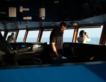 Un membro dell'equipaggio di MSF osserva e scruta l'orizzonte con il binocolo alla ricerca di imbarcazioni in difficoltà. (Geo Barents, febbraio 2022, @Kenny Karpov)
